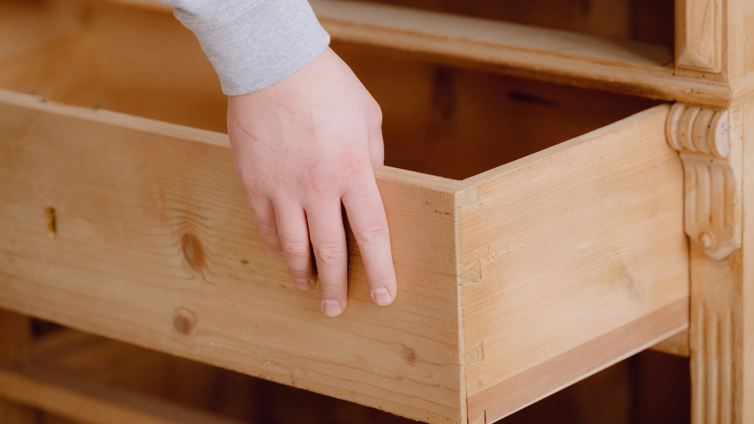Junger Lehrling, der eine Holzschublade in einen Holzschrank einlegt.